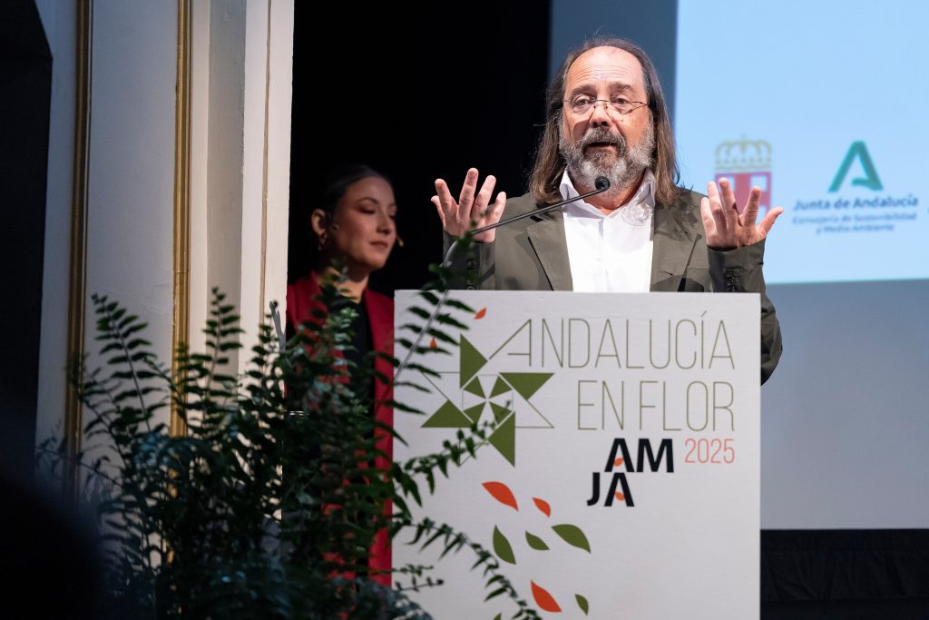 Hombre presentando en el evento Andalucía en Flor 2025 con logotipos de la Junta de Andalucía